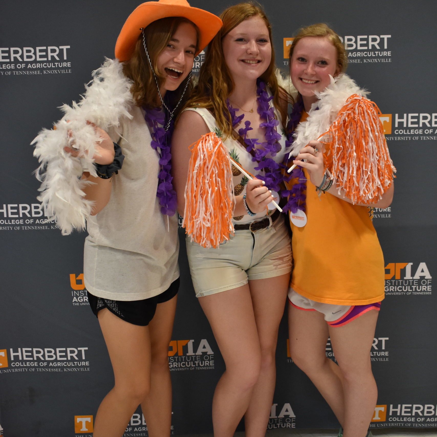 Students dressed in orange and white in front of Herbert College of Agriculture backdrop