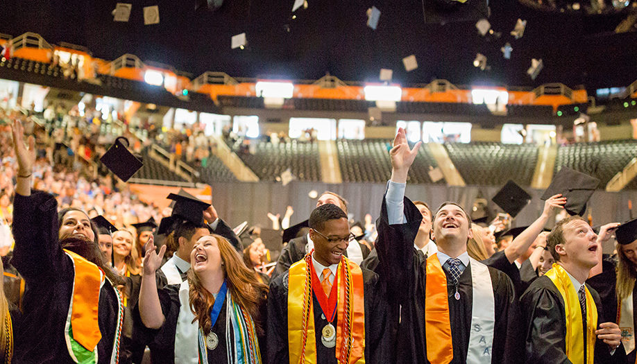 Graduates celebrating by tossing their caps in Thompson Boling Arena